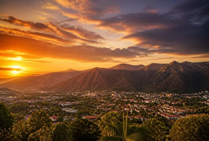 Atardecer dorado sobre la Serranía del Interior con la ciudad de Guatire en el valle, techos de tejas rojas y vegetación